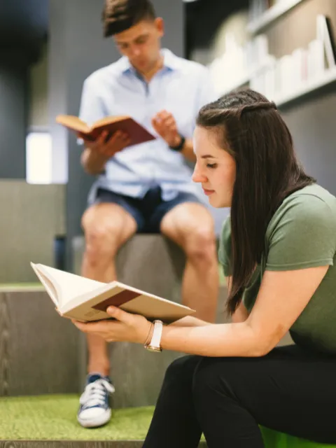 Two individuals enjoying books in a cozy reading area