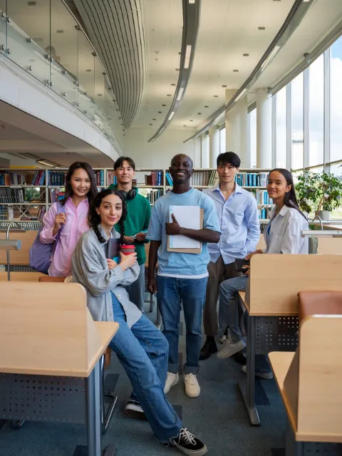 A diverse group of students smiling together in a library setting